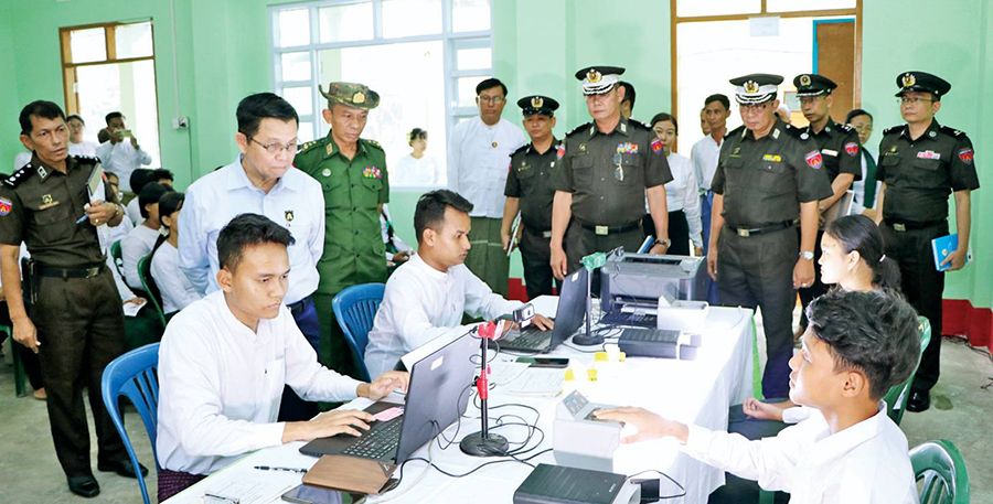 အိမ်မဲတွင် မှတ်ပုံတင် ပြုလုပ်နေမှုကို စစ်အာဏာရှင် လဝကဝန်ကြီး ဦးမြင့်ကြိုင် လိုက်ကြည့်နေစဉ်။ (Photos: KKL ၊ MOI)